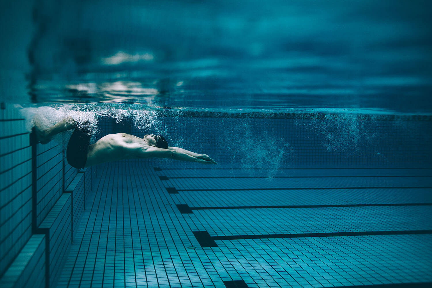 Private vs Group Swim Lessons: Which Is Better? Swimmer turning in a lane of a pool used for group swim lessons